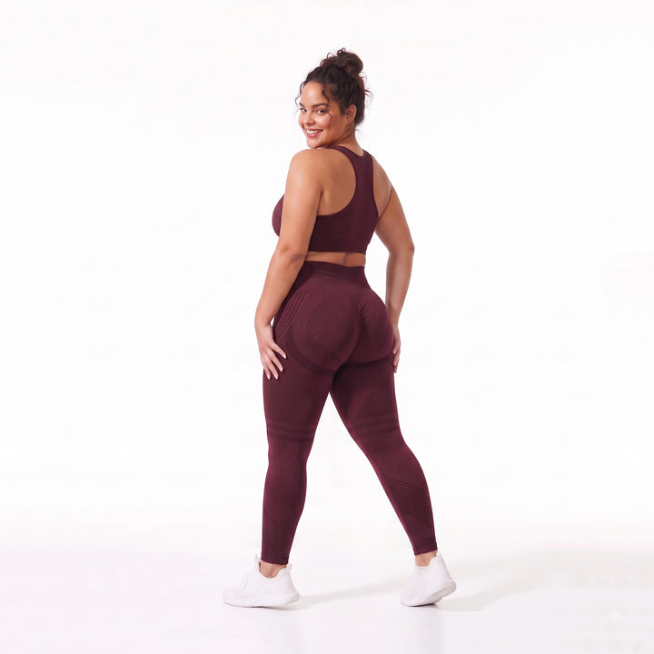 Mujer luciendo leggings anticelulítis color burdeos, destacando el tejido de compresión 3D y el efecto de firmeza natural en los glúteos.